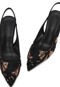Zwarte puntige slingback hakken met ingewikkelde zwarte en gouden pailletten- en kralenversieringen op het teengebied.