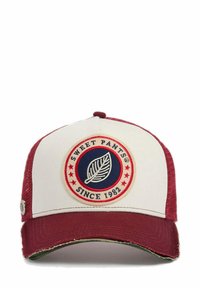 Casquette de baseball rouge et blanche avec un logo circulaire proéminent représentant une feuille, des côtés en maille texturée et une visière légèrement usée.