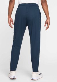 Tamsiai mėlyni sportiniai kelnės su siaurėjančia forma, elastinga juosmens dalimi, šoninėmis kišenėmis ir užsegamomis apačiomis. Pagamintos iš minkštos, tamprios medžiagos, užtikrinančios patogumą.