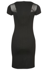 Robe noire moulante à manches courtes, avec des panneaux en maille transparente aux épaules et une fermeture éclair centrale dans le dos. Texture lisse, coupe ajustée.