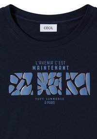 Chemise bleu marine avec l'étiquette « CECIL » et le texte français « L'avenir c'est maintenant, tout commence à Paris » avec des motifs abstraits bleus.