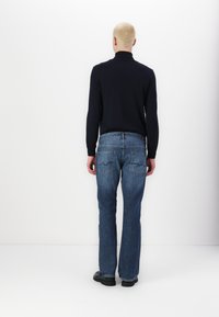 Dark navy long-sleeve turtleneck paired with blue denim straight-leg jeans. Flat and smooth texture; simple design with no visible patterns.