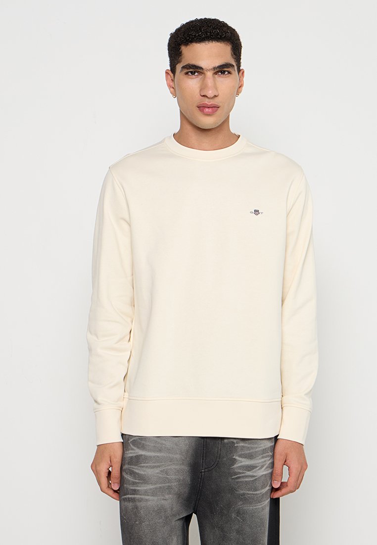 Hellbeige Sweatshirt aus weichem Stoff, mit Rundhalsausschnitt, langen Ärmeln und kleinem Logo auf der Brust. Reguläre Passform.