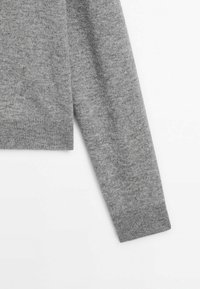 Manche longue en tricot gris de pull avec détail de bord-côte sur fond blanc.