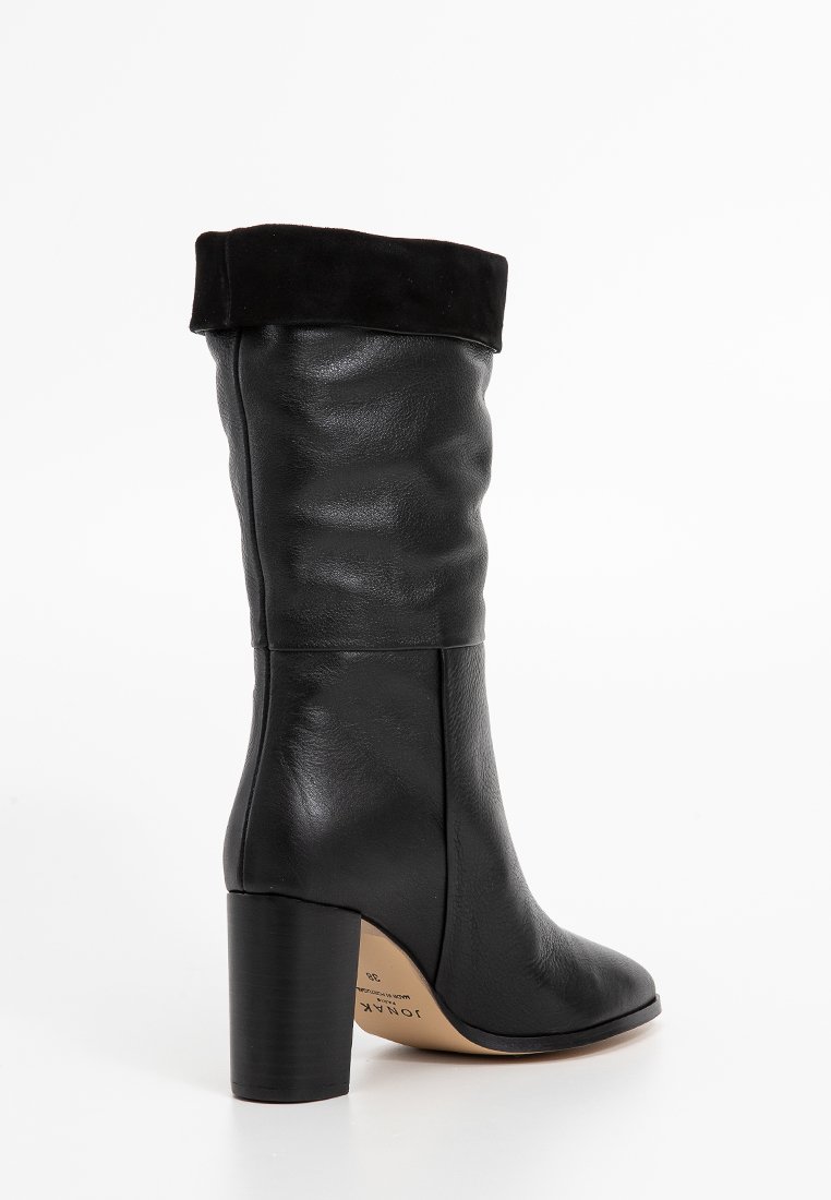 Bottes en cuir noires mi-mollet avec revers replié, bout arrondi et talon bloc, présentées de côté sur un fond blanc uni.