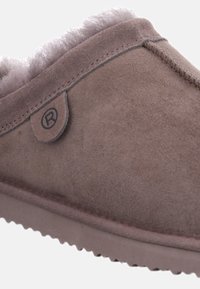 Bruna mockasiner i mocka med en mjuk, plyschig insida, sydda detaljer och en liten logotags på sidan. Rundad form med en platt sula.