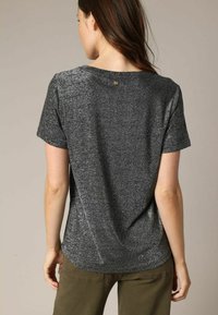 Grijze, kortge mouwen t-shirt met een losse fit, voorzien van een subtiele glans, ronde halslijn en een decoratieve knop op de rug.