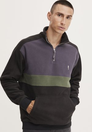 Fleece-pullover i svart, mørk grå og olivengrønn. Har en glidelås-krage, sidelommer og kontrasterende horisontalt stripedesign.