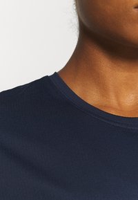 Mörkblå, figursydd t-shirt i texturerad tyg. Har rund halsringning och korta ärmar, med subtila sömdetaljer.