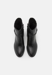 Bottines noires en cuir avec un bout pointu, des zips sur les côtés et une texture lisse. La doublure intérieure semble douce et moelleuse.