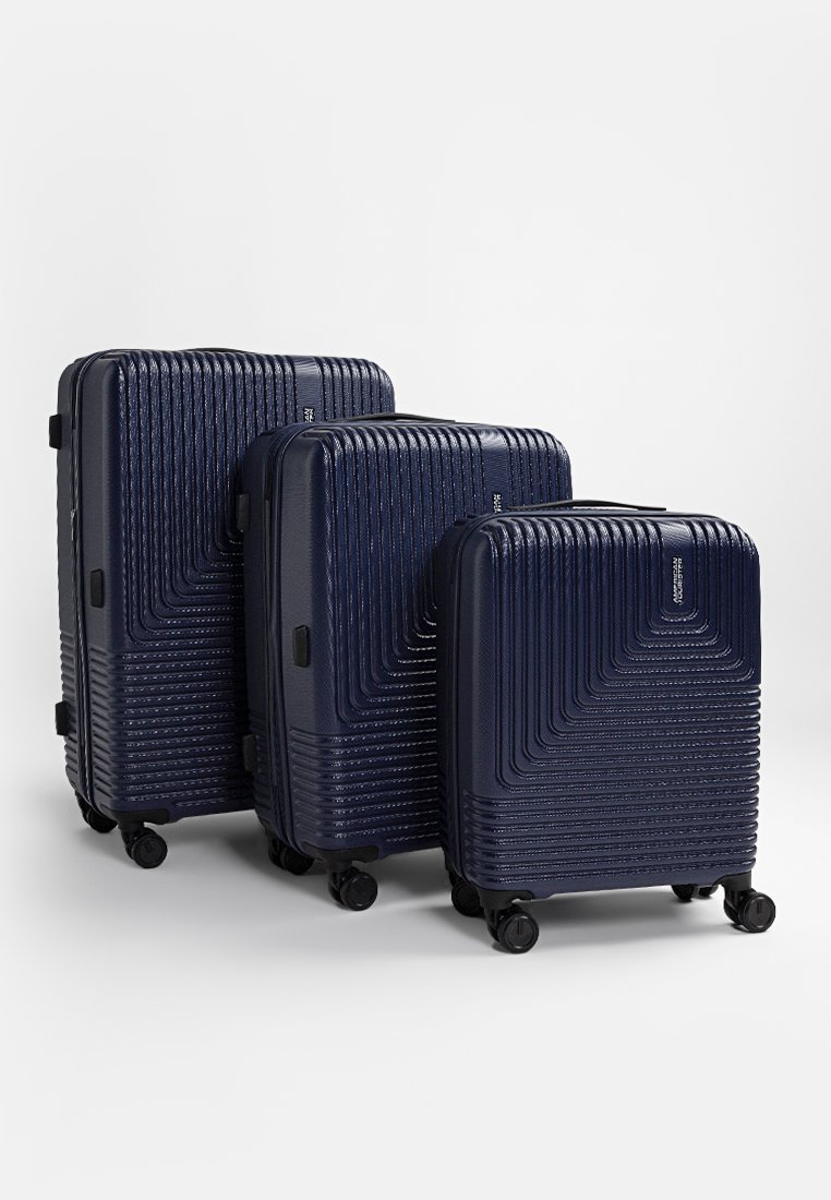 Conjunto de tres maletas rígidas en color azul marino con un diseño estriado texturizado. Cada una cuenta con cuatro ruedas y un asa retráctil para facilitar el transporte.