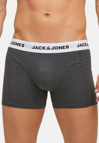 Graue Boxershorts aus weichem Stoff mit einem weißen elastischen Bund, der das "JACK & JONES"-Logo in Schwarz zeigt. Standardpassform und kurzes Bein-Design.
