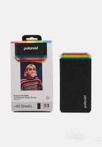 Polaroid Hi-Print φορητός εκτυπωτής φωτογραφιών σε μαύρο χρώμα με κορυφή που έχει ρίγες σε χρώματα του ουράνιου τόξου. Περιλαμβάνει συσκευασία και 40 φύλλα φωτογραφιών. Συμπαγής σχεδίαση.