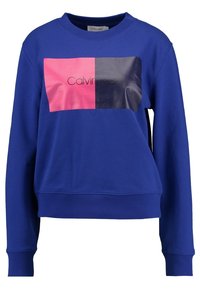 Modrý svetr s kulatým výstřihem, se skvělým grafickým designem kombinujícím růžové a tmavě modré části a logem uprostřed. Měkký materiál.