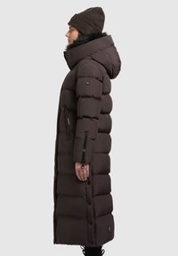 Cappotto puffer marrone con cappuccio, dotato di colletto in pelliccia sintetica, tasche laterali con zip e dettagli con bottoni a pressione lungo il davanti.