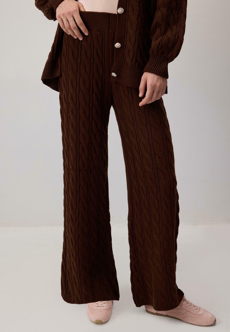Brown cable-knit sweater and matching wide-leg pants made from soft fabric. Notable silver buttons on the sweater; textured pattern throughout.