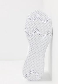 Suela de zapatilla de correr blanca con un patrón zigzag texturizado. Presenta detalles en gris y un logo en la base. Bordes suaves y ligera curvatura.