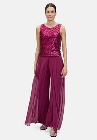 Haut en sequins fuchsia associé à un pantalon large en plum translucide. Il présente un design ajusté et une texture douce, avec des accents scintillants et un fluide élégant.