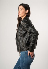 Zwarte leren jas met een slim fit ontwerp, voorzien van gevlochten accenten, schoudervullingen en contrasterende stiksels. Ritssluiting aan de voorkant.