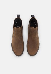 Paire de bottines marron en cuir à enfiler avec languettes de traction noires, bouts arrondis et panneaux latéraux élastiques, vues de dessus sur fond blanc.