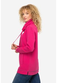 Jersey fucsia con un cuello alto, cordón, bolsillo frontal y aberturas laterales. Tejido suave y mangas largas; corte casual.