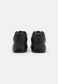 Schwarze Nike Air Sneakers mit strukturiertem Finish, gepolstertem Kragen und subtiler Markenkennzeichnung an der Ferse. Elegante, abgerundete Form mit einer glatten Sohle.