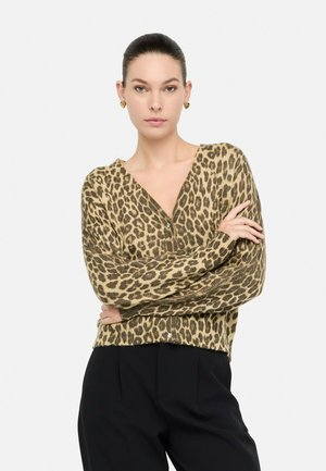 Maglione con stampa leopardata in tonalità beige e marrone, con maniche lunghe, scollo a V e vestibilità comoda. Indossato con pantaloni neri.