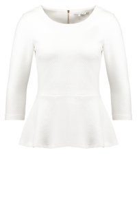 Weißes Peplum-Top mit Rundhalsausschnitt, langen Ärmeln und strukturiertem Stoff mit einem Diamantmuster. Mit Reißverschlussdetail auf der Rückseite.