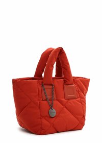 Red quilted handbag made of fabric, featuring dual fabric handles, leather accents, and a decorative chain with a round tag.