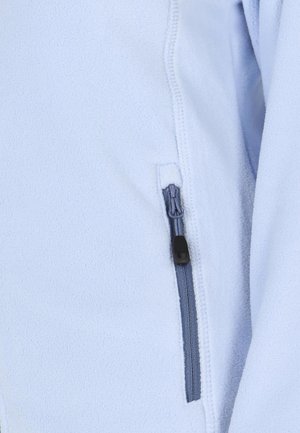 Chaqueta de polar azul claro con una textura suave. Cuenta con un bolsillo con cremallera de color gris y un detalle de tirador negro.