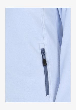 Lys blå fleecejakke med en glat tekstur. Har en lynlåslomme med en grå lynlås og sort greb.