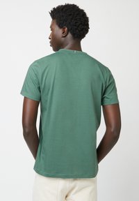 Grünes Kurzarm-T-Shirt mit einem einfachen Rundhalsausschnitt und geradem Saum. Hergestellt aus weichem Baumwollstoff mit einer feinen Textur.