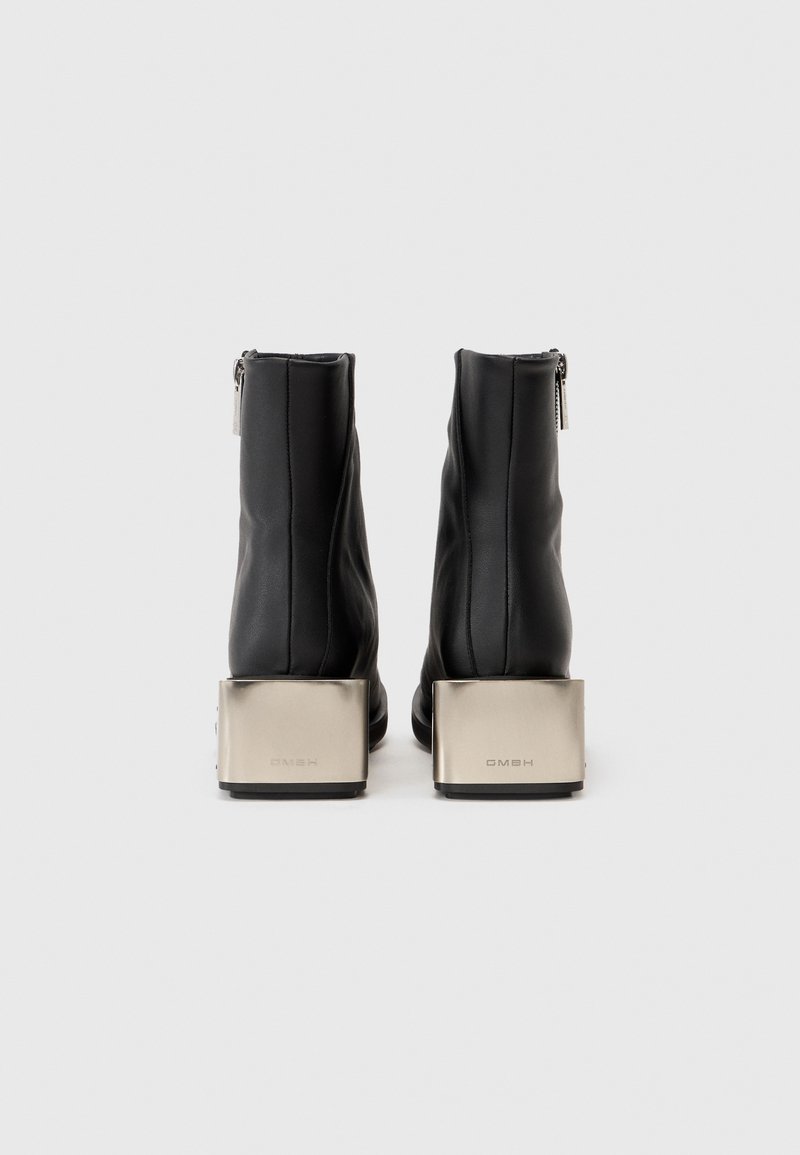 Schwarze Leder-Stiefeletten mit einem glänzenden silbernen Quadratfersen und Reißverschlussdetail. Glatte Textur mit vertikalen Nähten an den Seiten.