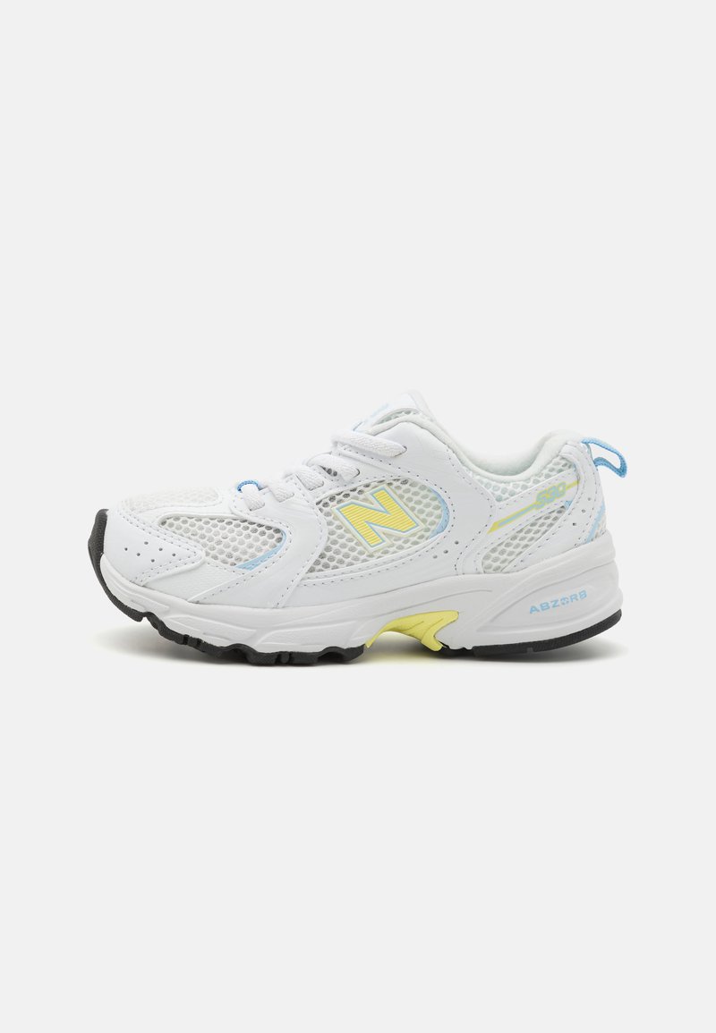 Hvite joggesko med mesh-paneler, gule og blå detaljer, rund tå, snøring og svart gummisåle. Merket på hælen sier "ABZORB."