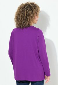 Lila Langarmoberteil mit entspannter Passform, rundem Halsausschnitt und glatter Oberfläche. Verfügt über seitliche Schlitze und einen weichen Stoff für zusätzlichen Komfort.