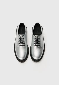 Zilveren leren schoenen met een gepolijste oppervlakte, zwarte veters en een gestructureerde zwarte rubberen zool. Beschikt over een afgeronde te ontwerp.
