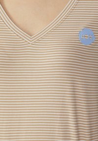 Beige T-shirt met V-hals en korte mouwen, voorzien van witte strepen en een blauw cirkelvormig "JOY"-logo. Zacht, glad materiaal met een lichte glans.
