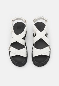 Witte geweven sandalen met kruisbandjes, zwarte rubberen zolen en een gevoerde voetbed. Het ontwerp beschikt over verstelbare enkelbandjes.