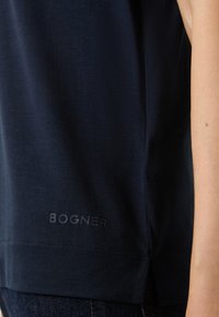 Námořnický top bez rukávů vyrobený z měkké látky, s rovnými lemy a jemným logem na spodní straně. Minimalistický design s minimálním šitím.