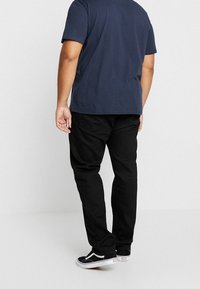 Černé kalhoty, námořnická košile, volný střih. Bavlněná směs s hladkou strukturou. Černé tenisky s bílými akcenty dokončují outfit.