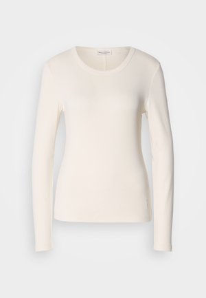 T-shirt à manches longues en coton crème, avec un col rond, une coupe ajustée et un petit logo près de l'ourlet. Texture lisse.