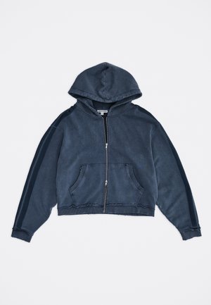 Sötétkék cipzáras kapucnis pulóver elülső zsebekkel, hosszú ujjakkal, melyeken sötétebb csíkok vannak, és csatolt kapucnival, egyszínű háttéren.