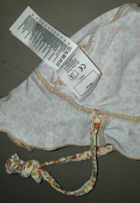 Bikinitop mit floralen Mustern aus weichem Stoff, mit weißem Grund und hellrosa Blumen, beigem Nähen und verknoteten Trägern mit bunten Akzenten.