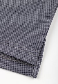 Tumedasinise tekstuuriga teksariie, millel on korralik ääreõmblus ja kontrastne tikk äärte ääres.