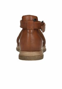 Brown leather ankle boot with a smooth texture, adjustable strap, and a light tan rubber sole. Rear view shows rounded heel and minimal stitching.