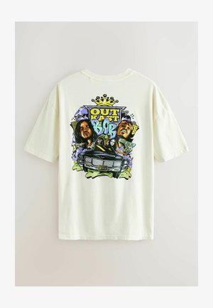 T-shirt en coton crème clair avec un design graphique coloré mettant en scène des personnages, une voiture, et le texte "OUT KAST" et "BOB" en typographie audacieuse.