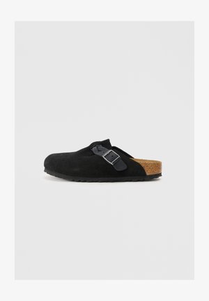 Μαύρο σουέτ παπούτσι slip-on με φελλό σόλα, με πλευρική λεπτομέρεια από πόρπη και σχέδιο στρογγυλής μύτης. Λατρευτή, υφασμένη σόλα από καουτσούκ.