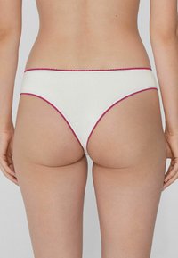 White cotton bikini underwear with a low rise, featuring a magenta scalloped trim along the waistband and leg openings.