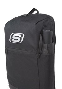 Mochila negra hecha de tejido duradero, que presenta un bolsillo con cremallera y un soporte lateral para un paraguas. Logotipo exhibido de manera prominente en plata.