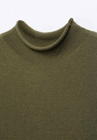 Pull en maille vert olive avec un col montant doux, légèrement roulé, et une texture côtelée fine.